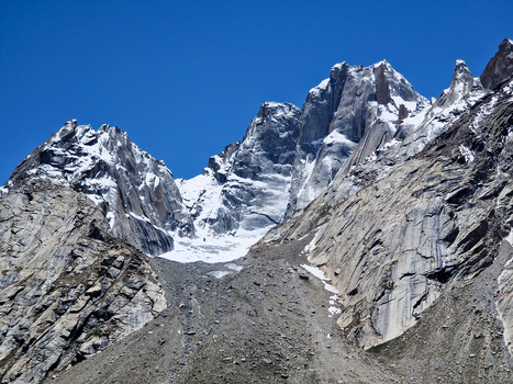 View of the rugged snow capped peaks of the Zanskar range with steep rocky slopes and a glacier nestled in the mountain pass in Zanskar Ladakh India.