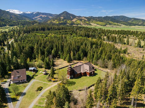 Aerial view of the Wooden Articular Church of Svaty Kriz surrounded by a lush evergreen forest and snow capped mountains in Svaty Kriz Zilinsky kraj Slovakia.