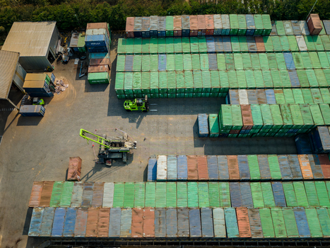 Aerial view of a large container yard featuring rows of stacked shipping containers a forklift and a crane in an industrial storage area in Boyolali Central Java Indonesia.