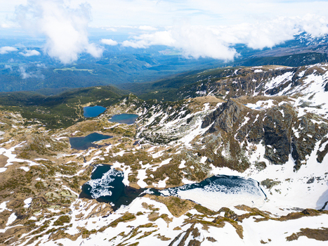 Aerial view of the Seven Rila Lakes featuring glacial lakes surrounded by snow capped peaks and rocky terrain in Kyustendil Province Bulgaria. Aerial view of the Seven Rila Lakes featuring glacial lakes surrounded by snow capped peaks and rocky terrain in Kyustendil Province Bulgaria.