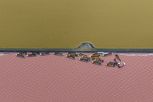 Aerial view of boats contrasting against the pink salt lake and adjacent yellow waters creating a striking visual divide San Pedro del Pinatar Region of Murcia Spain. Aerial view of boats contrasting against the pink salt lake and adjacent yellow waters creating a striking visual divide San Pedro del Pinatar Region of Murcia Spain.
