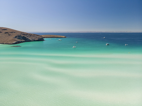 Aerial view of Balandra beach with its turquoise shallow waters sandy seabed patterns and boats anchored in the bay La Paz Baja California Sur Mexico. Aerial view of Balandra beach with its turquoise shallow waters sandy seabed patterns and boats anchored in the bay La Paz Baja California Sur Mexico.