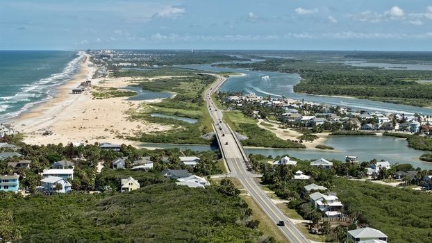 Aerial view of Matanzas Inlet showing the bridge coastal dunes lush vegetation and residential homes along the Atlantic coastline in St. Johns County Florida United States. Aerial view of Matanzas Inlet showing the bridge coastal dunes lush vegetation and residential homes along the Atlantic coastline in St. Johns County Florida United States.