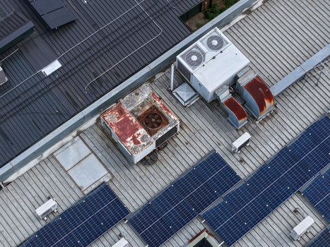 Melbourne Australia 25 September 2026 Aerial view of an industrial rooftop featuring weathered HVAC units rusted ventilation ducts and rows of solar panels.
