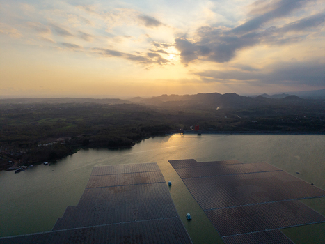 Aerial view of floating solar panels on the Sutami Dam reservoir at sunset with rolling hills in the background in Kecamatan Sumberpucung Jawa Timur Indonesia. Aerial view of floating solar panels on the Sutami Dam reservoir at sunset with rolling hills in the background in Kecamatan Sumberpucung Jawa Timur Indonesia.