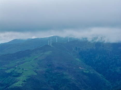 Aerial view of wind turbines standing on green mountain ridges under a thick layer of low clouds and mist Cudillero Asturias Spain.