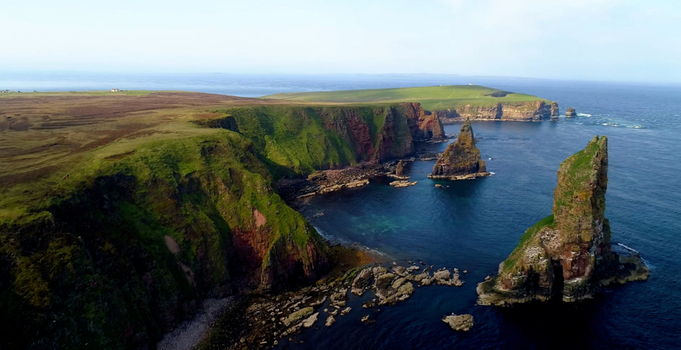 Aerial view of Duncansby Stacks featuring dramatic sea cliffs rugged coastline and deep blue ocean waters in John o Groats Highland Council United Kingdom. Aerial view of Duncansby Stacks featuring dramatic sea cliffs rugged coastline and deep blue ocean waters in John o Groats Highland Council United Kingdom.