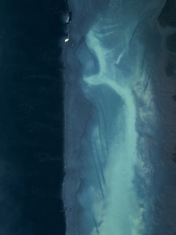 Aerial view of the coastline of Iceland featuring deep blue ocean waters transitioning into shallow turquoise coastal currents and dark volcanic sand patterns Iceland. Aerial view of the coastline of Iceland featuring deep blue ocean waters transitioning into shallow turquoise coastal currents and dark volcanic sand patterns Iceland.