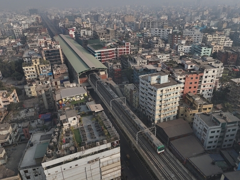 Aerial view of the Dhaka Metro Rail train moving along the elevated track through the dense urban cityscape of Dhaka Dhaka Division Bangladesh. Aerial view of the Dhaka Metro Rail train moving along the elevated track through the dense urban cityscape of Dhaka Dhaka Division Bangladesh.