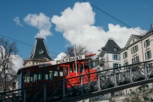 Zurich Switzerland 02 April 2023 View of the bright red Polybahn funicular ascending its steep track a vibrant contrast against the city s architecture and the clear blue sky. Zurich Switzerland 02 April 2023 View of the bright red Polybahn funicular ascending its steep track a vibrant contrast against the city s architecture and the clear blue sky.