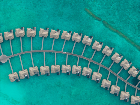 Aerial view of overwater bungalows stretch out into the turquoise ocean their thatched roofs a stark contrast to the vibrant water Hoarafushi Thiladhunmathee Uthuruburi Maldives. Aerial view of overwater bungalows stretch out into the turquoise ocean their thatched roofs a stark contrast to the vibrant water Hoarafushi Thiladhunmathee Uthuruburi Maldives.