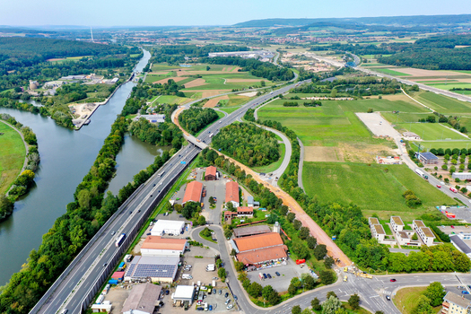 Aerial view of the A73 motorway bridge crossing the Main Donau Kanal with surrounding industrial buildings and green agricultural fields in Forchheim Bayern Germany. Aerial view of the A73 motorway bridge crossing the Main Donau Kanal with surrounding industrial buildings and green agricultural fields in Forchheim Bayern Germany.