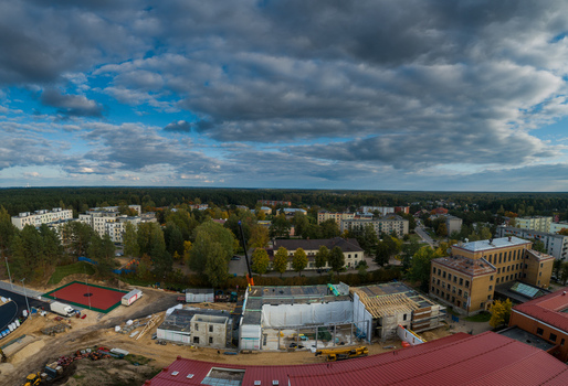 Aerial view of a construction site with a crane and building materials surrounded by residential houses trees and a sports court in Latvia. Aerial view of a construction site with a crane and building materials surrounded by residential houses trees and a sports court in Latvia.