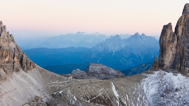 Aerial view of Tre Cime di Lavaredo with jagged rocky peaks and snow covered slopes under a soft twilight sky Auronzo di Cadore Veneto Italy. Aerial view of Tre Cime di Lavaredo with jagged rocky peaks and snow covered slopes under a soft twilight sky Auronzo di Cadore Veneto Italy.