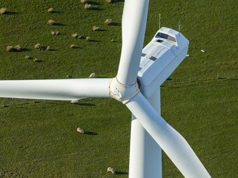 Aerial view of a white wind turbine nacelle and blades over green pastures with grazing sheep in Scotland United Kingdom. Aerial view of a white wind turbine nacelle and blades over green pastures with grazing sheep in Scotland United Kingdom.