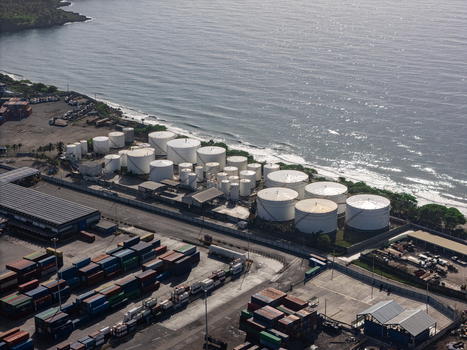 Aerial view of the industrial port with white storage tanks colorful shipping containers and the Caribbean Sea coastline in Bajos de Haina San Cristobal Provinc Dominican Republic.