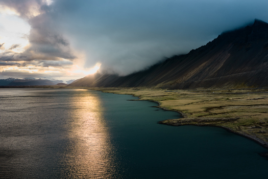 Aerial view of Vestrahorn mountain reflecting the golden hour light over the coastal waters with dramatic clouds Hornafjordur Iceland. Aerial view of Vestrahorn mountain reflecting the golden hour light over the coastal waters with dramatic clouds Hornafjordur Iceland.