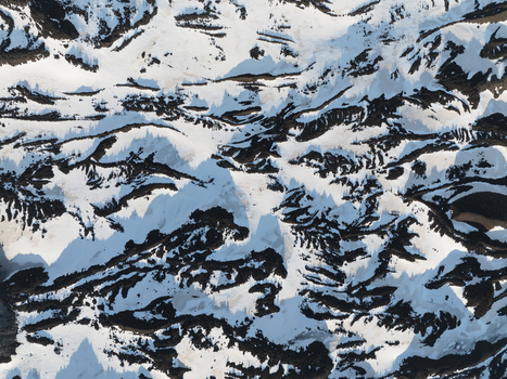 Aerial view of Versante sud dell Etna with snow covered slopes and dark volcanic rock formations creating a natural abstract pattern Nicolosi Sicilia Italy. Aerial view of Versante sud dell Etna with snow covered slopes and dark volcanic rock formations creating a natural abstract pattern Nicolosi Sicilia Italy.