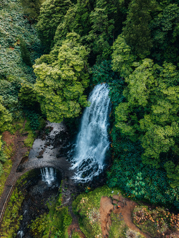 Aerial view of water cascading down the rocks framed by the lush greenery of the surrounding forest Achada Açores Portugal. Aerial view of water cascading down the rocks framed by the lush greenery of the surrounding forest Achada Açores Portugal.