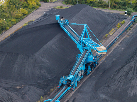 Aerial view of a large blue stacker machine operating on a massive coal pile at an industrial mining site in Berlin Berlin Germany.