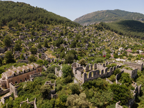 Aerial view of the historic ghost village of Kayakoy with its abandoned stone houses and ruins nestled on a hillside surrounded by lush greenery in Fethiye Mugla Turkiye. Aerial view of the historic ghost village of Kayakoy with its abandoned stone houses and ruins nestled on a hillside surrounded by lush greenery in Fethiye Mugla Turkiye.
