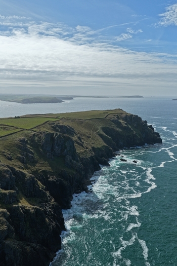 Aerial view of The Rumps a dramatic coastal headland with rugged cliffs grassy fields and crashing waves along the Atlantic coast in Wadebridge England United Kingdom. Aerial view of The Rumps a dramatic coastal headland with rugged cliffs grassy fields and crashing waves along the Atlantic coast in Wadebridge England United Kingdom.