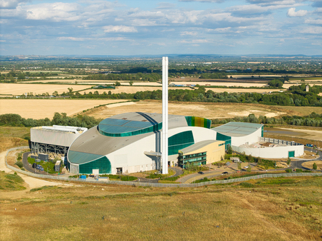 Aerial view of the Energy Recovery Facility featuring modern industrial architecture with a tall chimney and green glass situated amidst rural fields in Bicester England United Kingdom.