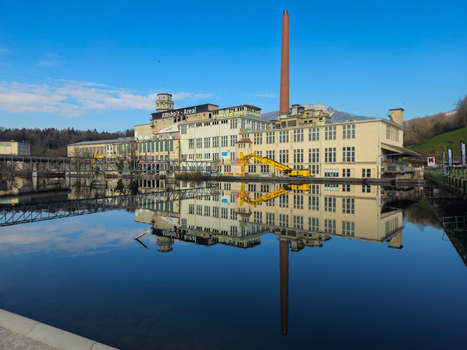 View of the Former Cellulose Factory Attisholz Areal reflecting in the calm river water under a clear blue sky in Solothurn Solothurn Switzerland. View of the Former Cellulose Factory Attisholz Areal reflecting in the calm river water under a clear blue sky in Solothurn Solothurn Switzerland.