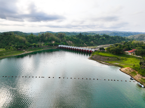 Rangamati Hill District Bangladesh 18 May 2024 Aerial view of Kaptai Lake dam surrounded by lush green hills and calm turquoise water under a cloudy sky.
