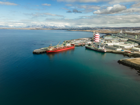 Hafnarfjordur Iceland 17 April 2026 Aerial view of the industrial port area featuring large cargo ships docked at the pier industrial facilities and snow capped mountains under a cloudy sky. Hafnarfjordur Iceland 17 April 2026 Aerial view of the industrial port area featuring large cargo ships docked at the pier industrial facilities and snow capped mountains under a cloudy sky.