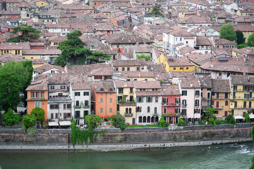 Aerial view of colorful historic buildings along the Adige river with terracotta rooftops and lush green trees in the old town of Verona Veneto Italy.
