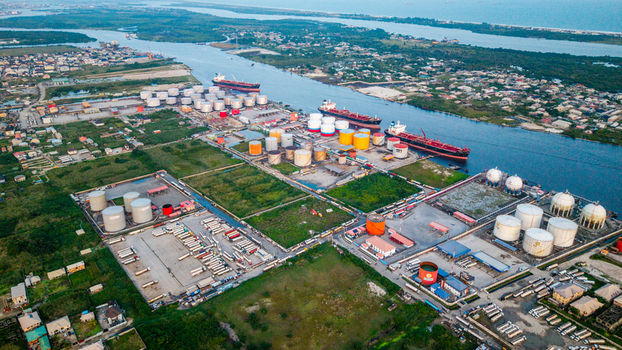Aerial view of the industrial port and storage tank facility in Satellite Town with cargo ships tanker trucks in the yard and urban development in Lagos Lagos Nigeria.