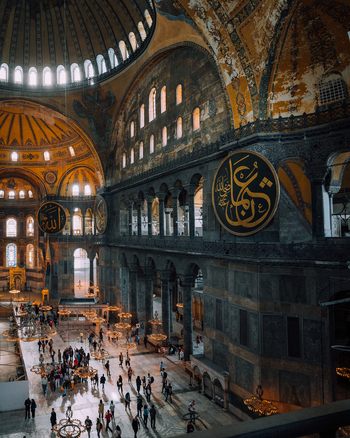 Istanbul Turkiye 07 October 2019 View of the grand Hagia Sophia its majestic dome casting a warm glow upon the bustling crowds below a dance of light and shadow within ancient walls.