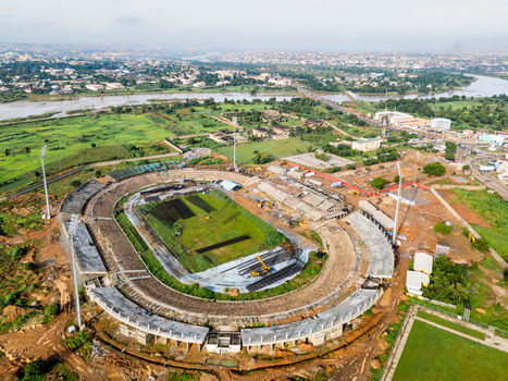 Aerial view of Ahmadu Bello Stadium undergoing renovation with construction equipment on the field surrounded by lush greenery urban infrastructure and a river in Kaduna Kaduna Nigeria. Aerial view of Ahmadu Bello Stadium undergoing renovation with construction equipment on the field surrounded by lush greenery urban infrastructure and a river in Kaduna Kaduna Nigeria.