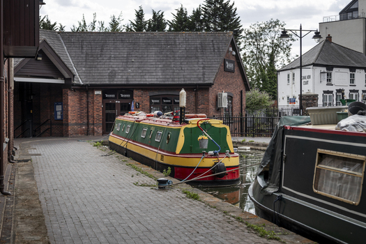 Coventry England United Kingdom 20 July 2026 View of colorful narrowboats moored along the canal basin featuring traditional brick architecture and a paved walkway.