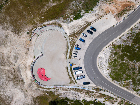 Aerial view of the heart shaped Panorama Llogora viewpoint with parked cars and a winding mountain road in Himare Qarku i Vlores Albania.