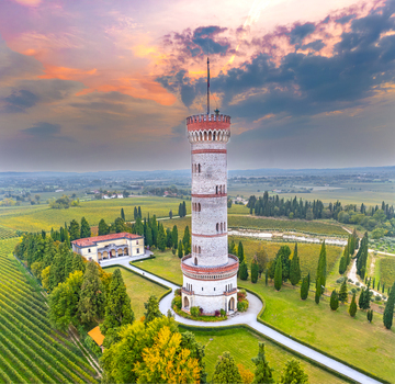 Aerial view of the Tower of San Martino della Battaglia surrounded by vineyards cypress trees and a historic building under a sunset sky in San Martino della Battaglia Lombardia Italy. Aerial view of the Tower of San Martino della Battaglia surrounded by vineyards cypress trees and a historic building under a sunset sky in San Martino della Battaglia Lombardia Italy.