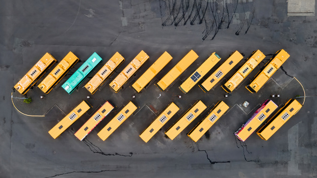 Aerial view of a bus depot with rows of yellow buses parked in an orderly pattern on asphalt in Reykjavik Reykjavikurborg Iceland.