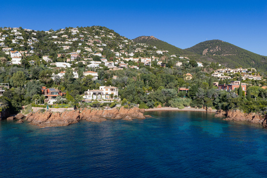 Aerial view of Le Trayas featuring luxury villas on the rocky coastline with lush greenery red cliffs and the blue Mediterranean Sea in Saint Raphael Provence Alpes Cote d Azur France. Aerial view of Le Trayas featuring luxury villas on the rocky coastline with lush greenery red cliffs and the blue Mediterranean Sea in Saint Raphael Provence Alpes Cote d Azur France.