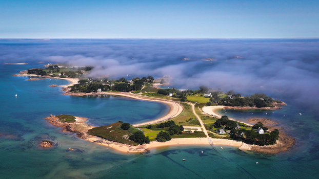 Aerial view of &Icirc;le Callot shrouded in ethereal mist a tapestry of emerald islets fringed by azure waters Carantec Brittany France.