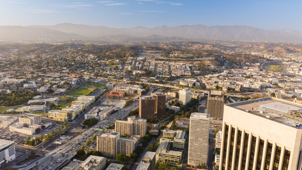 Aerial view of the Los Angeles cityscape featuring high rise office buildings sprawling residential neighborhoods and busy highways under a clear sky in Los Angeles California United States.