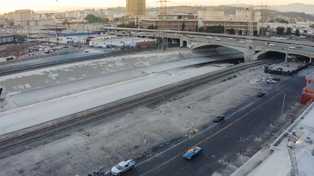 Aerial view of the Los Angeles River concrete channel with adjacent railway tracks a highway bridge with traffic and urban surroundings in Los Angeles California United States. Aerial view of the Los Angeles River concrete channel with adjacent railway tracks a highway bridge with traffic and urban surroundings in Los Angeles California United States.