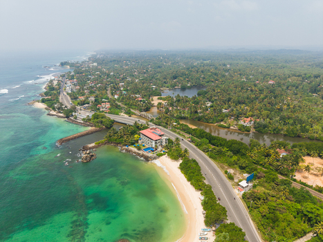 Aerial view of Devil s Rock a coastal road and lush tropical vegetation along the turquoise shoreline in Ahangama Southern Province Sri Lanka. Aerial view of Devil s Rock a coastal road and lush tropical vegetation along the turquoise shoreline in Ahangama Southern Province Sri Lanka.