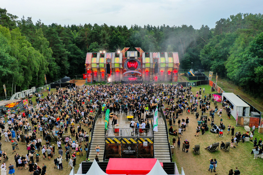 Herzogenaurach Germany 26 July 2025 Aerial view of the Open Beatz Festival with a large crowd gathered in front of a stage surrounded by dense forest.