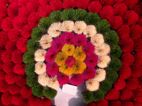 Aerial view of colorful incense sticks arranged in vibrant circular patterns of red green yellow and pink creating a striking geometric display in Vietnam. Aerial view of colorful incense sticks arranged in vibrant circular patterns of red green yellow and pink creating a striking geometric display in Vietnam.