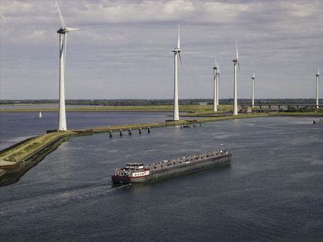 Aerial view of a cargo ship navigating the waterway alongside the Grevelingendam dam with wind turbines in the background in Bruinisse Zeeland Netherlands. Aerial view of a cargo ship navigating the waterway alongside the Grevelingendam dam with wind turbines in the background in Bruinisse Zeeland Netherlands.