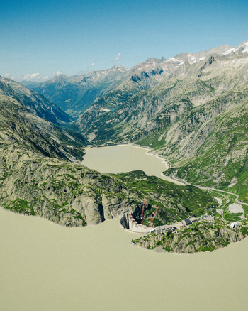 Aerial view of the Grimselsee dam and reservoir surrounded by the rugged peaks and green slopes of the Swiss Alps Guttannen Canton of Bern Switzerland.