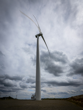 View of Harapaki Wind Farm with a large wind turbine featuring rotating blades set against a cloudy sky in Te Haroto Hawke s Bay Region New Zealand. View of Harapaki Wind Farm with a large wind turbine featuring rotating blades set against a cloudy sky in Te Haroto Hawke s Bay Region New Zealand.