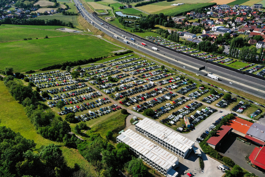 Aerial view of the Eventzentrum Strohofer Geiselwind musichall featuring a large parking lot filled with cars next to the highway and green fields in Geiselwind Bayern Germany. Aerial view of the Eventzentrum Strohofer Geiselwind musichall featuring a large parking lot filled with cars next to the highway and green fields in Geiselwind Bayern Germany.