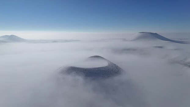 Aerial view of volcanic cones emerging from thick fog Turkiye.